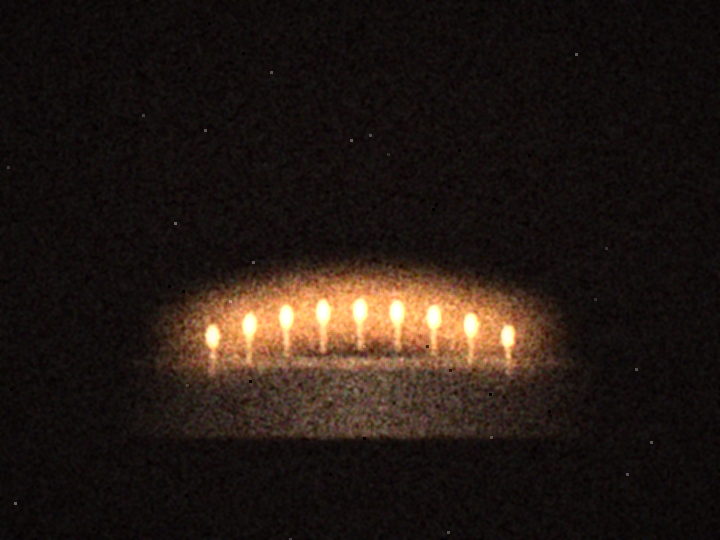 Nine lit candles on a cake in a dark room